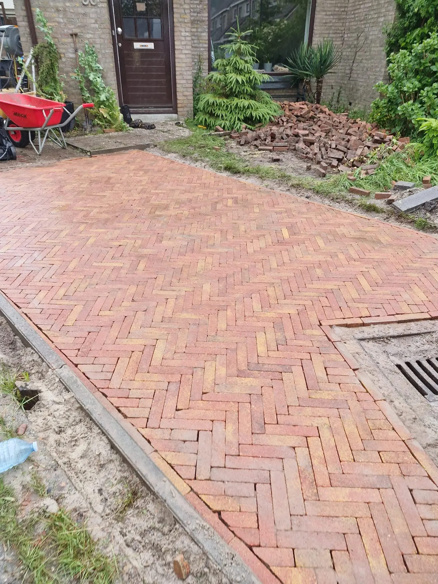 Rode klinkers in keperverband, strak rond een putdeksel gezaagd