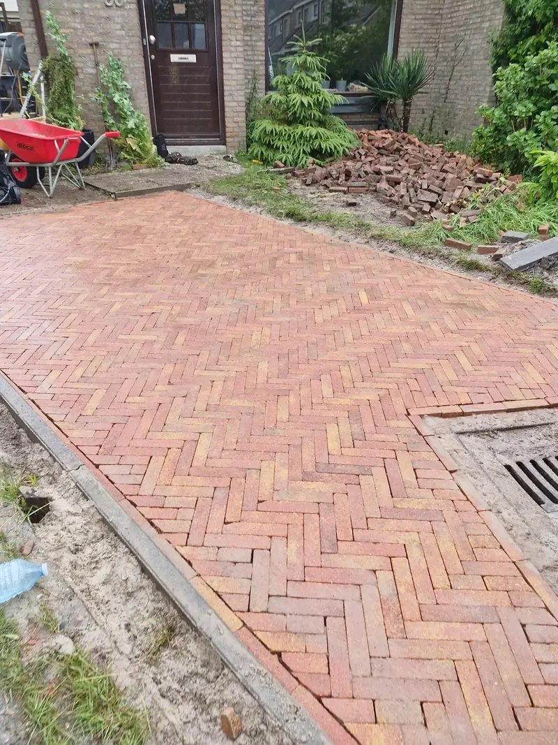 Rode klinkers in keperverband rond een putdeksel